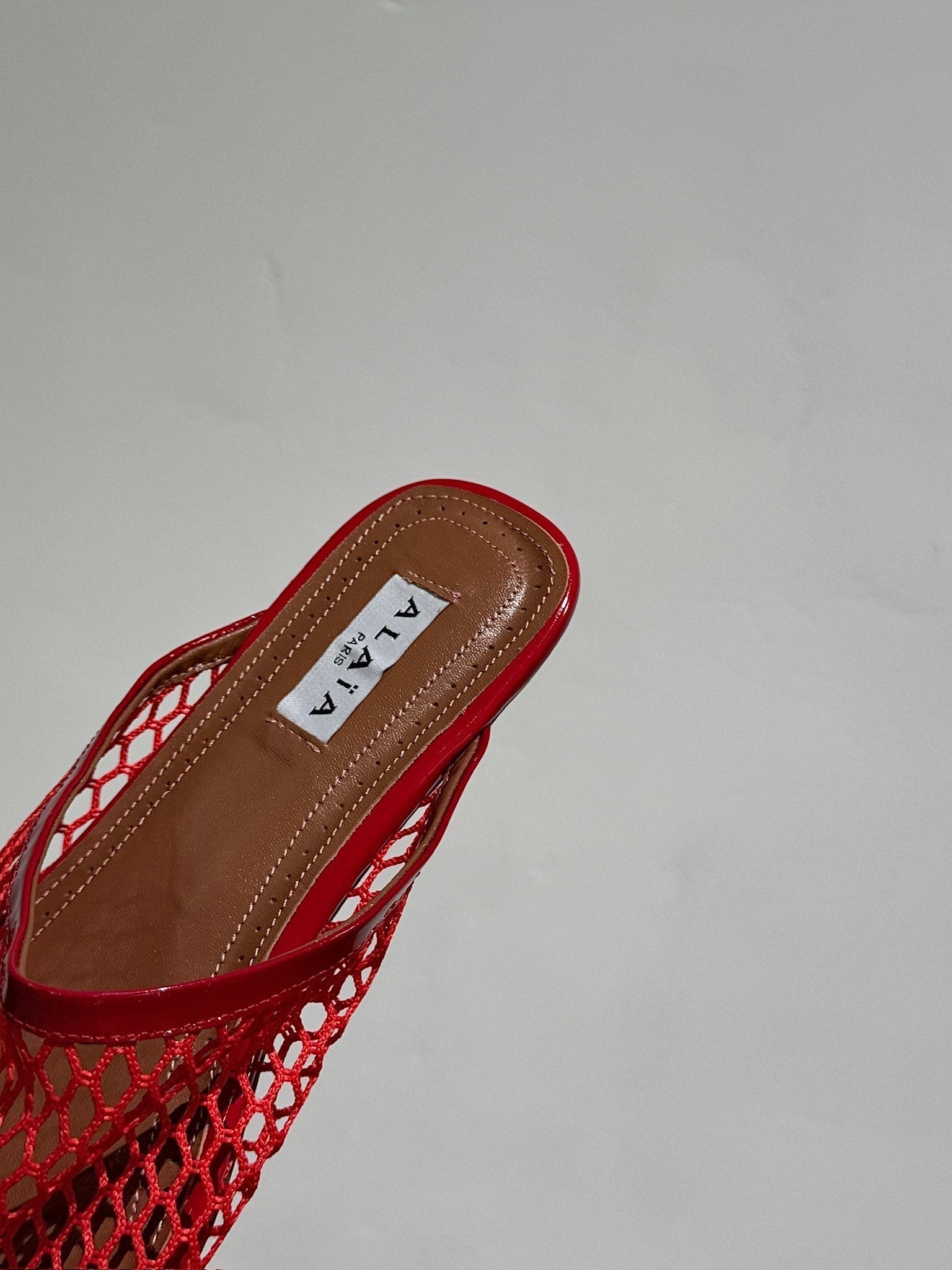 ALAIA FLAT MULES IN CHERRY RED MESH FISHNET